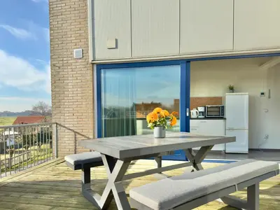 a picnic table with two benches on a deck with a kitchen at Appartementen Casa del Lago in Lisse