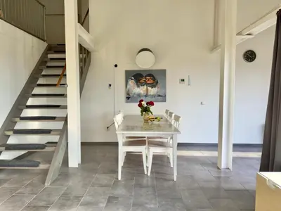 a dining room with a white table and stairs at Appartementen Casa del Lago in Lisse