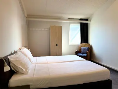 a bedroom with a large white bed and a chair at Appartementen Casa del Lago in Lisse