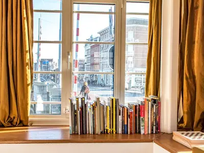 a row of books on a shelf in front of a window at SWEETS - Willemsbrug in Amsterdam