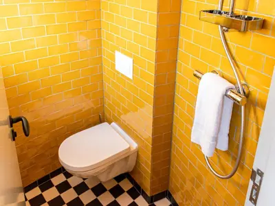 a yellow tiled bathroom with a toilet and a shower at SWEETS - Willemsbrug in Amsterdam