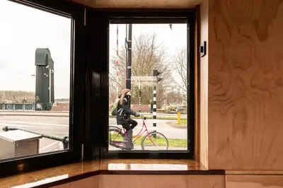 a woman walking a bike through a window at SWEETS - Omvalbrug in Amsterdam