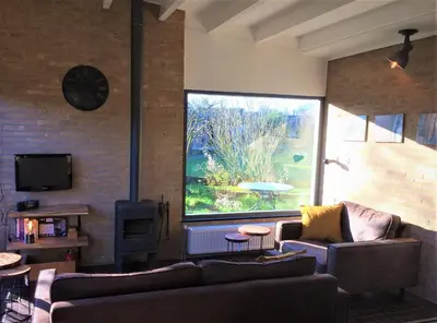 a living room with two couches and a large window at Bungalow 221 in Noordwijkerhout