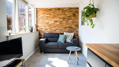 a living room with a couch and a brick wall at B&B Joeys place in Egmond aan Zee