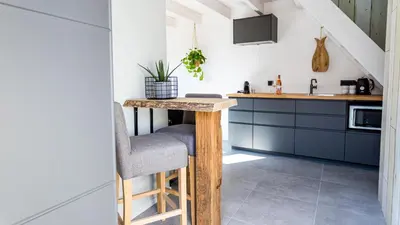 a kitchen with blue cabinets and a table with a chair at B&B Joeys place in Egmond aan Zee