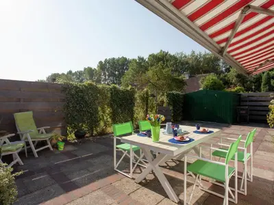 a patio with a table and green chairs at Holiday Home in Noordwijkerhout near Beach in Noordwijkerhout
