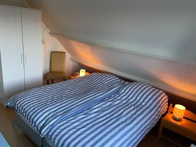 a bedroom with a bed with a striped comforter at Holiday Home in Noordwijkerhout near Beach in Noordwijkerhout