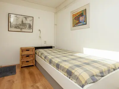 a small bedroom with a bed and a night stand at Holiday Home in Noordwijkerhout near Beach in Noordwijkerhout