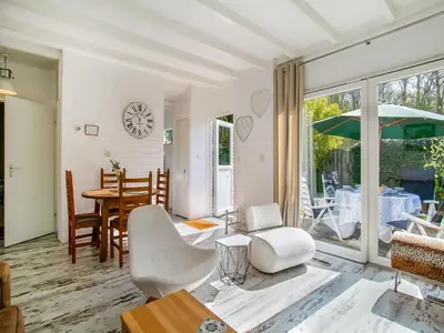 a living room with white chairs and a table at Bungalow in Noordwijk near Beaches in Noordwijkerhout
