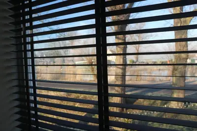 a window with blinds looking out at a yard at Mooi appartement in een prachtige fiets-wandelomgeving in Abcoude