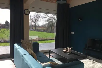 a living room with a blue couch and a table at Ruim appartement in prachtige fiets-wandelomgeving in Abcoude