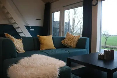 a living room with a blue couch and a table at Ruim appartement in prachtige fiets-wandelomgeving in Abcoude