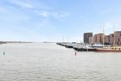 a group of boats docked in a harbor with buildings at B&B Houseboat Amsterdam in Amsterdam