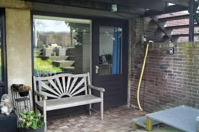 a porch with a white chair and a door at Have a nice stay! - Souterrain The Freesia in Noordwijk