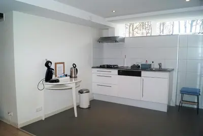 a white kitchen with a sink and a stove at Have a nice stay! - Souterrain The Freesia in Noordwijk