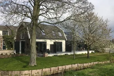 a house with a tree in the yard at Landelijk appartement in een mooi recreatiegebied in Abcoude