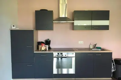 a kitchen with black cabinets and a stainless steel oven at Landelijk appartement in een mooi recreatiegebied in Abcoude