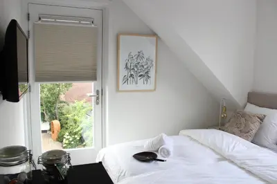 a bedroom with a white bed and a window at Hotel Paradis Zandvoort in Zandvoort