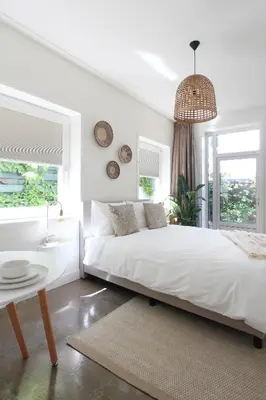 a white bedroom with a bed and a table at Hotel Paradis Zandvoort in Zandvoort