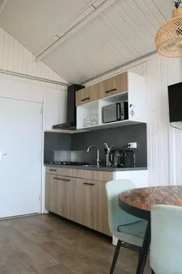 a kitchen with a sink and a table with chairs at Willy Zuid in Katwijk aan Zee
