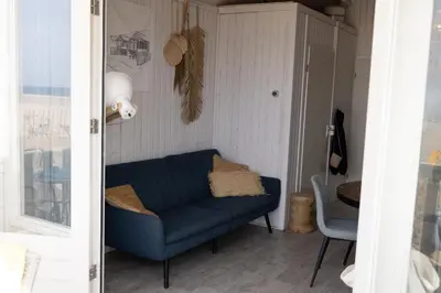 a living room with a blue couch and a chair at Willy Zuid in Katwijk aan Zee