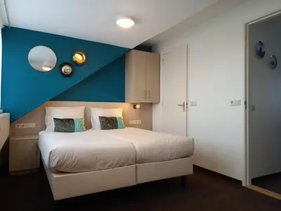 a bedroom with a bed with a blue accent wall at Zeevonk Studio's & Appartementen in Katwijk aan Zee