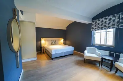 a bedroom with a bed and a chair and a mirror at Fletcher Hotel-Restaurant De Oude Gevangenis-Alkmaar in Alkmaar