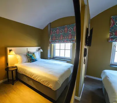a small bedroom with a bed and a window at Fletcher Hotel-Restaurant De Oude Gevangenis-Alkmaar in Alkmaar