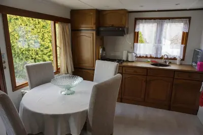 a kitchen with a white table and chairs and a kitchen with a window at Chalet at a holiday park in Opmeer near Amsterdam in Opmeer