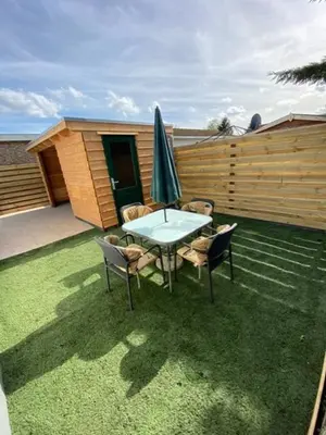 a patio with a table and chairs and an umbrella at Chalet at a holiday park in Opmeer near Amsterdam in Opmeer