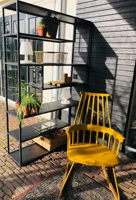 a yellow chair sitting in front of a book shelf at 'Room Eleven' aan de Vecht in Vreeland