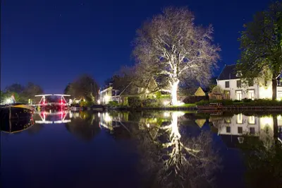 a night view of a house and a lake at 'Room Eleven' aan de Vecht in Vreeland