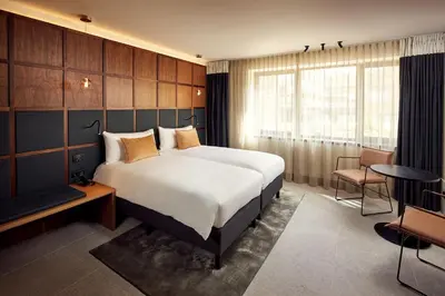 a hotel room with a bed and a desk and a window at Met Hotel Amsterdam in Amsterdam