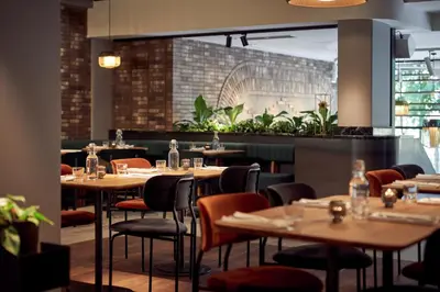 a restaurant with wooden tables and chairs and plants at Met Hotel Amsterdam in Amsterdam