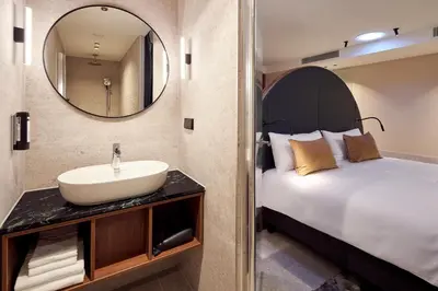 a bathroom with a bed and a sink and a mirror at Met Hotel Amsterdam in Amsterdam