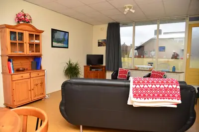 a living room with a black couch and a table at Bas Apartment Egmond aan Zee in Egmond aan Zee