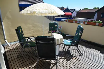 a table and chairs on a balcony with an umbrella at Bas Apartment Egmond aan Zee in Egmond aan Zee