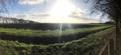 a field with the sun shining on the horizon at Polderhoek in Woubrugge