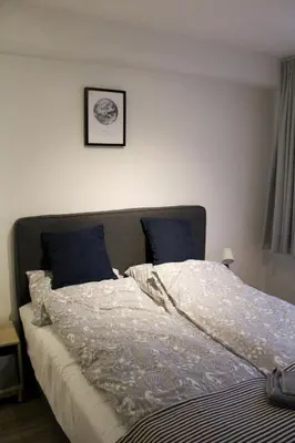 a bed with white sheets and blue pillows on it at Polderhoek in Woubrugge
