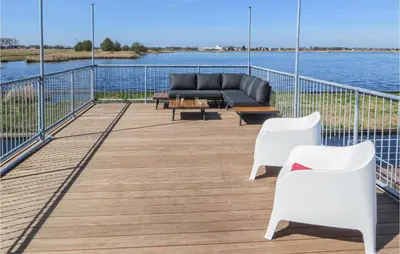 a deck with a couch and chairs on the water at Bluff in Aalsmeer