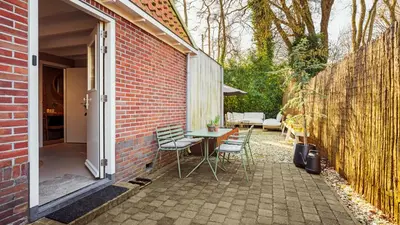 a patio with a table and chairs next to a brick wall at Casa de la Pelt in Bergen