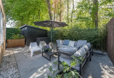 a patio with a couch and an umbrella at Casa de la Pelt in Bergen