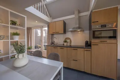 a kitchen with wooden cabinets and a table with a vase at De Grote Stern in Groet