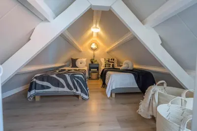 a attic bedroom with two beds and a ceiling at De Grote Stern in Groet