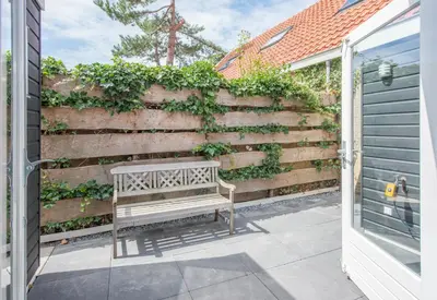 a bench sitting on a patio next to a retaining wall at De Grote Stern in Groet