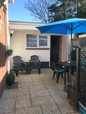 a patio with a table and chairs and an umbrella at Mikasabeach in Zandvoort