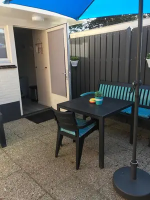 a table and a bench with an umbrella on a patio at Mikasabeach in Zandvoort