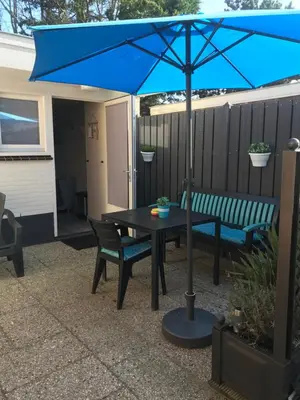 a blue umbrella over a table and a bench at Mikasabeach in Zandvoort