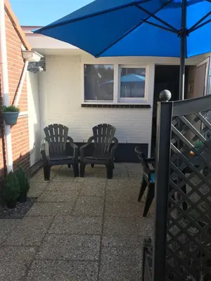 two chairs and a table with a blue umbrella at Mikasabeach in Zandvoort