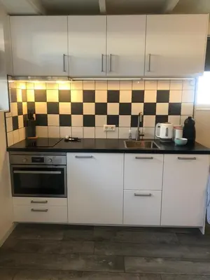 a kitchen with white cabinets and black and white tiles at Mikasabeach in Zandvoort